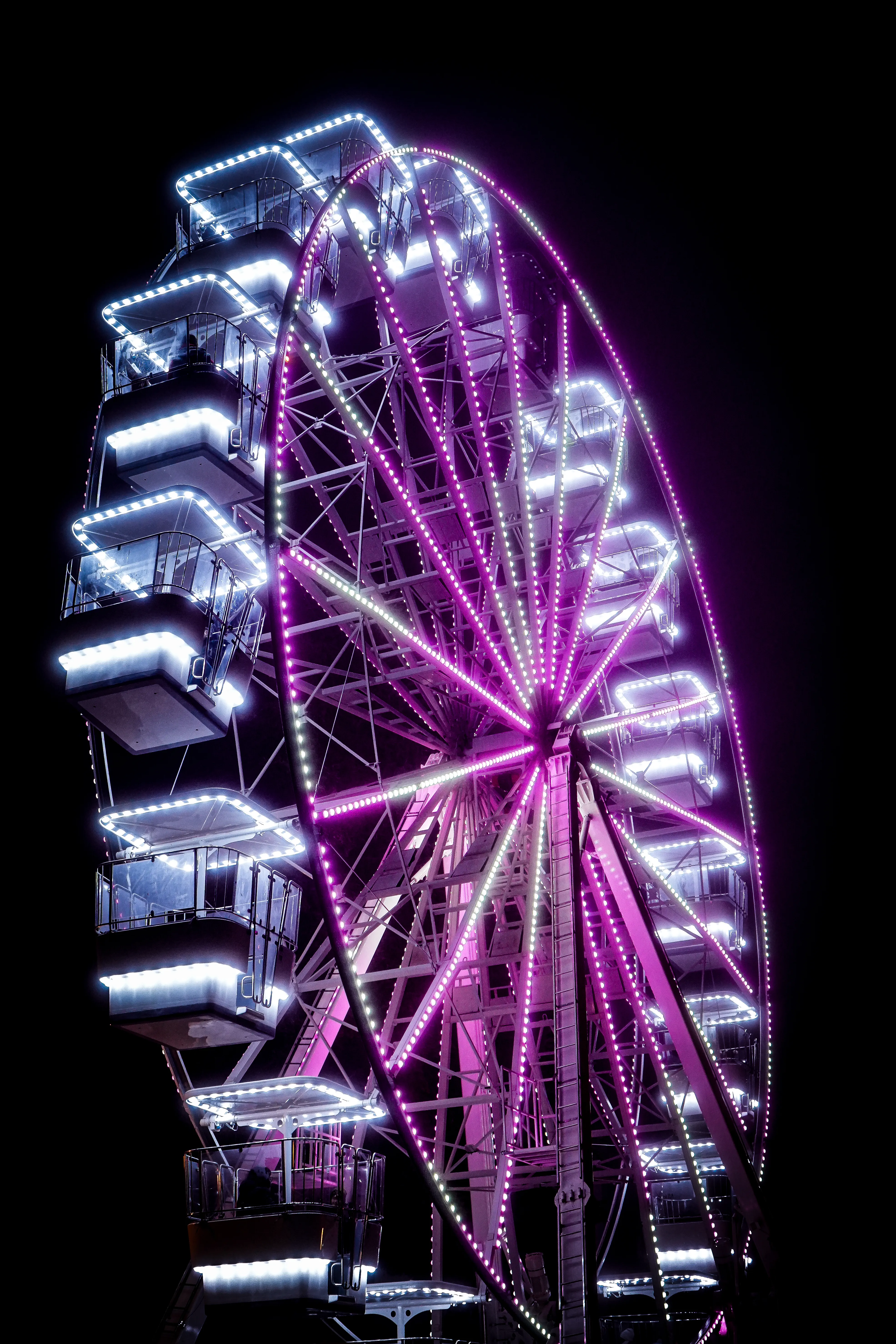 A brightly lit Ferris wheel at an amusement park after dark